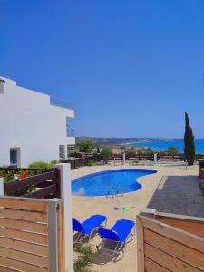 - une piscine avec des chaises bleues et l'océan dans l'établissement 3 Bedroom Seaview Villa direct in Coral Bay with Pool, à Coral Bay