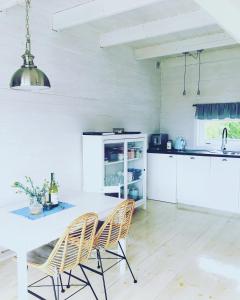 a white kitchen with a white table and chairs at Apartamenty Pogodna in Łeba