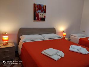 a bedroom with a red bed with towels on it at Avola Holidays in Avola