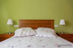 a bed with two pillows on it with two lamps at Apartamento el Peral A in Colombres