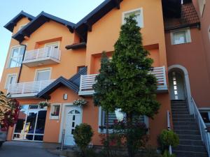 a orange house with a tree in front of it at Apartments Luke in Dubrave Gornje