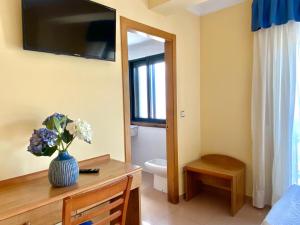 a bathroom with a toilet and a vase of flowers on a table at Duerming Areas Playa Hotel in Sanxenxo