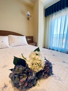 a bouquet of flowers sitting on top of a bed at Duerming Areas Playa Hotel in Sanxenxo