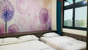 two beds in a room with purple flowers on the wall at 牧雲民宿 in Jinning