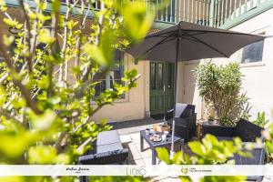 une terrasse avec un parasol, une table et des chaises dans l'établissement gardenhill, à Argelès-Gazost