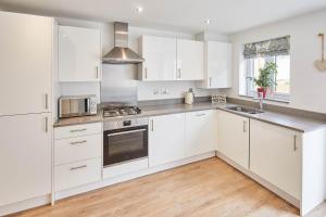 una cocina blanca con armarios blancos y fregadero en Host & Stay - Castle View en Durham