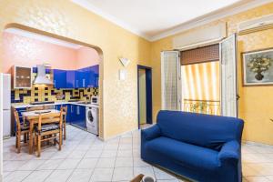 a living room with a blue couch and a kitchen at Corte dei Mori in Avola +14 photos