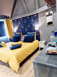 a bedroom with a large yellow bed with blue pillows at Les Rêves by Isa in Arras