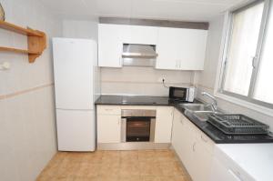 a kitchen with a white refrigerator and a sink at Adosado Puntamer Orangecosta in Peñíscola