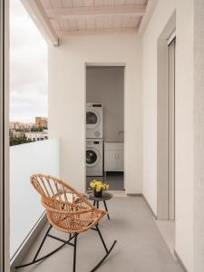 une chaise en osier assise sur un balcon avec une table dans l'établissement Living u HomeSuites, à Lecce