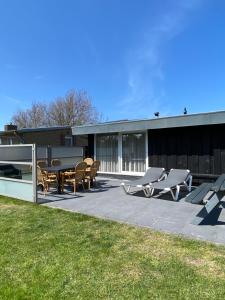 a patio with a table and chairs and a building at Bungalow Sunny, lekker uitwaaien op het strand! in Callantsoog