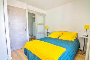 Schlafzimmer mit einem Bett mit gelber und blauer Bettwäsche in der Unterkunft Le Pop in Saint-Julien-Chapteuil