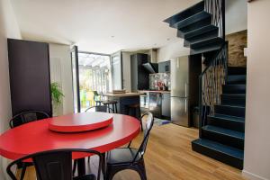 einen roten Tisch und Stühle in einem Zimmer mit einer Treppe in der Unterkunft Le Pop in Saint-Julien-Chapteuil