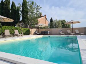 a swimming pool with chairs and umbrellas at Apartmani Gržinić in Rovinj