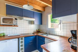 eine Küche mit blauen Schränken und einer Mikrowelle in der Unterkunft Ty Tevenn in Telgruc-sur-Mer