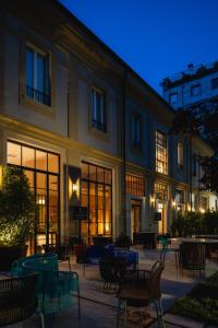 a building with tables and chairs in a courtyard at night at Vmaison Brera Milano in Milan