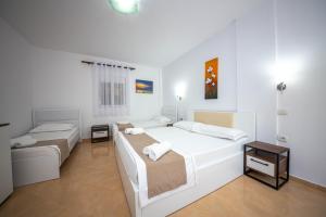 a white room with two beds and a table at Noan Hotel & Resort in Dhërmi