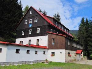 a large black and white barn with a red roof at Hotel Flora Dolní Mísečky in Dolni Misecky