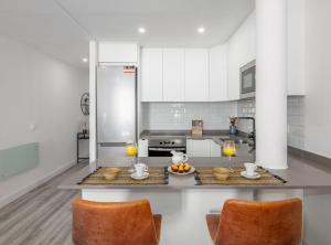 a kitchen with white cabinets and orange chairs at Cozy apartment for 2 City center MADERA I in Madrid