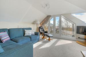 a living room with a blue couch and a tv at Sandpiper in Lyme Regis