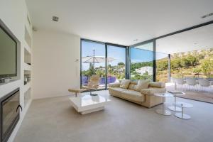 ein Wohnzimmer mit Couch, Tischen und Fenstern in der Unterkunft Nature Villa in Alcúdia