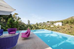 einen Pool mit lila Stühlen und einem Sonnenschirm in der Unterkunft Nature Villa in Alcúdia
