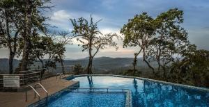 a swimming pool with a view of the mountains at The Porcupine Castle Resort in Madikeri