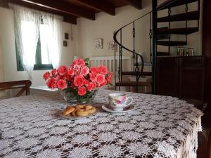 a table with a vase of red roses and a cup of coffee at Vivian's House for relaxing holidays in Nature in Kissamos