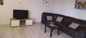 a living room with a black leather couch and a tv at Villa Maria in Marconia