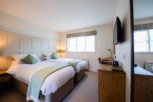 a hotel room with two beds and a television at The Coach and Horses in Oxford