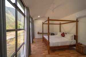 a bedroom with a canopy bed and a large window at The Ayali Riverside Resort in Rishīkesh