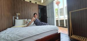 a woman sitting on a bed in a bedroom at Khang Homestay in Da Nang