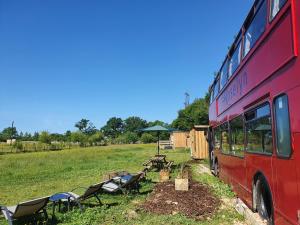 a red bus parked in a field with tables and chairs at Double Decker Bus on an Alpaca farm sleeps 8 in Bovey Tracey