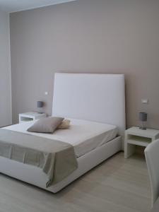 a white bedroom with a white bed and two tables at Ledwars in Taviano