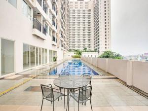 a table and chairs on a balcony in a building at RedLiving Apartemen Margonda Residence 5 - Ens Room with Netflix and Breakfast in Kemirimuka Tiga