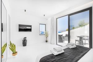 a white bedroom with a bed and a balcony at Tagoo Black Mykonos in Mýkonos City