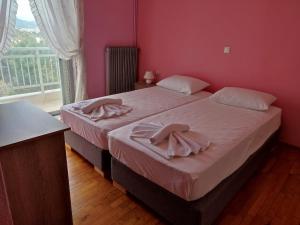 a bedroom with two beds with pink walls and a window at THEA COURT Clio & Erato Apartments in Paleo Tsifliki