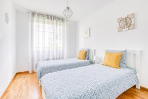 two beds in a room with white walls and wood floors at Cosy appartement Proche Disneyland Paris in Montévrain