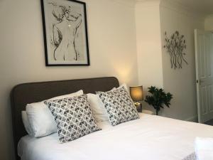una camera da letto con letto, lenzuola e cuscini bianchi di 2 Bedroom Apartment in Central Windsor a Windsor