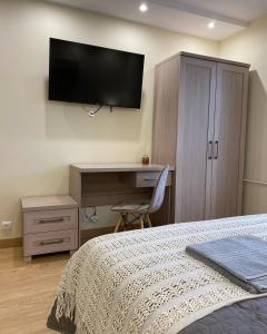 a bedroom with a bed and a desk with a television on the wall at MARCO Apartment 8 in Giżycko