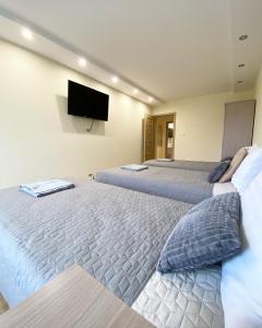 two beds in a room with a tv on the wall at MARCO Apartment 8 in Giżycko