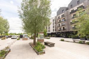 a courtyard with a tree and benches and a building at Cosy appartement Proche Disneyland Paris in Montévrain