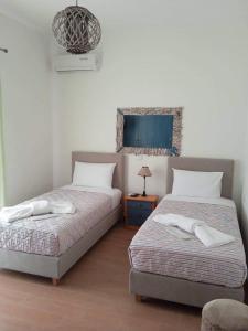 Villazia Exclusive Estate في Episkopianá: غرفة نوم بسريرين وطاولة بها مصباح