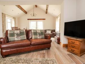 a living room with a brown leather couch and a flat screen tv at Batty Hole Farm in Burnley