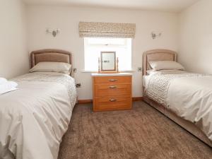 two beds in a room with a mirror and a dresser at Batty Hole Farm in Burnley