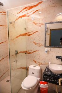a bathroom with a toilet and a sink and a shower at The Govindam Resort in Vrindāvan
