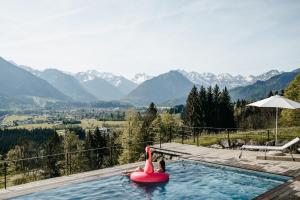 a pink flamingo in a swimming pool with a view of mountains at Der Jägersberg in Fischen