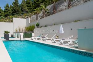 einen Pool mit Liegestühlen und einem Pool in der Unterkunft Villa Smaragd - Perle - Luxury Apartments With Shared Pool in Makarska
