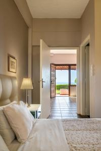 a bedroom with a bed and a door leading to a patio at Beachfront Family Villa Katerina with Private pool, Playground, BBQ & Amazing Sea Views! in Petres +68 photos