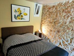 una camera con letto e parete in pietra di Les Pieds dans l'eau, Gîte la Source a Lachapelle-Auzac